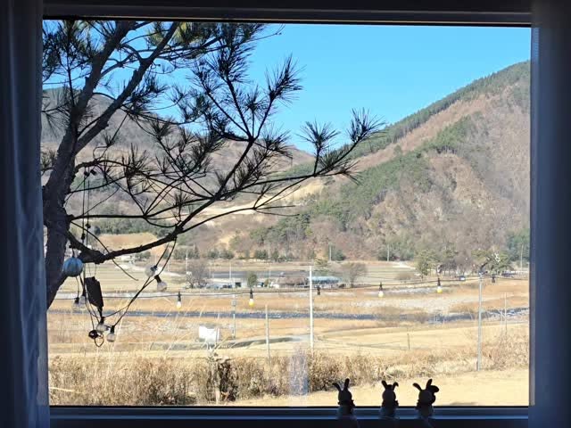 숙소 침실 창문 너머로 보이는 산과 시골 풍경